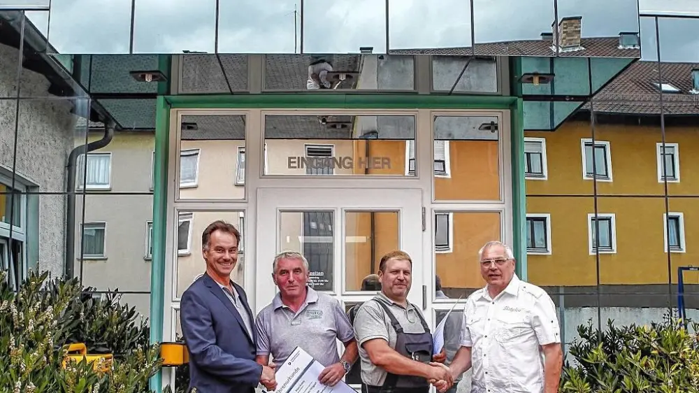Team von Hutter Glas- & Fenstertechnik vor dem Firmengebäude, Übergabe einer Jubiläumsurkunde